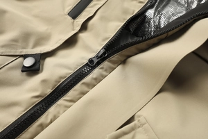 Dettaglio macro della giacca outdoor kaki con zip nera e fodera argentata a nido d'ape
