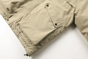 Dettaglio della giacca outdoor kaki con tasca cargo a patta, bottoni automatici e coulisse