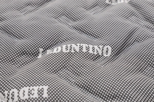 Dettaglio del tessuto trapuntato grigio con pois bianchi e logo DUNTINO per parka invernale