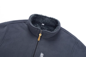 Dettaglio della giacca in pile grigio scuro con collo alto, zip e logo frontale