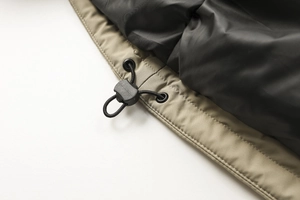 Dettaglio del cappuccio regolabile su giacca outdoor kaki con cordoncino e occhielli
