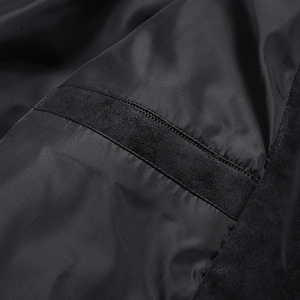 Detailopname van de gladde zwarte nylon voering en suède getextureerde binnennaden van de jas