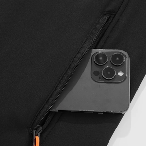 Detail van softshelljack met ritszak, oranje trekker en opbergruimte voor een smartphone