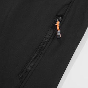 Detail van outdoorjas met winddichte stof en zwarte rits met oranje trekkoord bovenaan