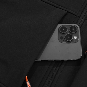 Detail van een functionele ritszak met oranje trekkoord op de zwarte softshell jas