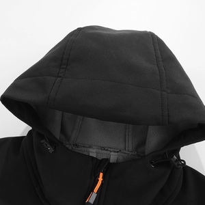 Detail van outdoorjas met capuchon, grijze fleecevoering en oranje ritsaccenten op de stof