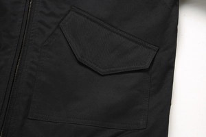 Detailopname van katoenen twill met hoge dichtheid, metalen rits en klepzakken op jas
