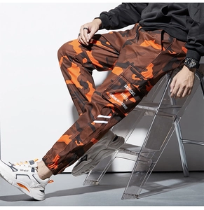 Détail du pantalon cargo camouflage orange avec de grandes poches latérales et ourlet