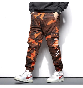 Détail du pantalon cargo camouflage avec grandes poches à rabat et texte blanc