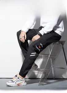 Détail du pantalon cargo noir avec broderie sur poche latérale et rayures sur jambe