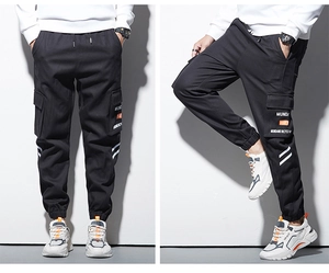 Détail du pantalon cargo noir avec grandes poches latérales et texte MUNDANE blanc