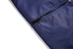 Detail of navy flight jacket with smooth fabric texture and contrasting orange lining