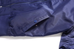 Detailed close-up of dark blue bomber jacket with smooth zipper and button pocket