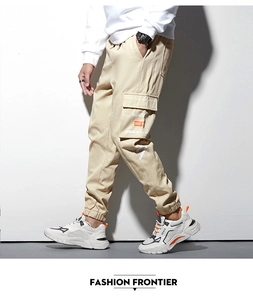Détail du jogging cargo kaki montrant la poche de jambe avec texte Mundane et accents orange