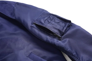 Detailed close-up of navy blue flight jacket sleeve with MA-1 style zippered utility pocket