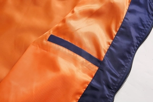 Detailed macro view of vibrant orange jacket lining with navy trim and inner pocket