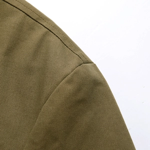 Dettaglio della spalla di un blazer in cotone verde oliva con cuciture doppie rinforzate