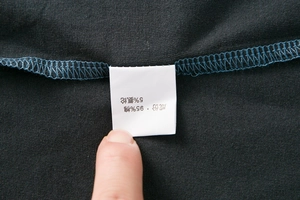 Detailansicht des Etiketts mit 95% Baumwolle und 5% Elasthan auf dem Herren-Poloshirt