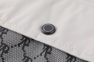 Détail d'une veste d'hiver grise avec bouton pression noir et texte collection