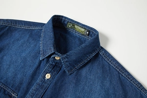 Dettaglio colletto camicia in denim blu con etichetta outdoor e bottoni in legno
