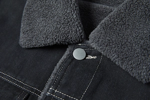 Dettaglio giacca in denim nero con fodera in pile grigio e cuciture a contrasto
