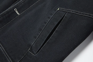 Dettaglio della tasca della giacca di jeans nera con doppie cuciture bianche a contrasto