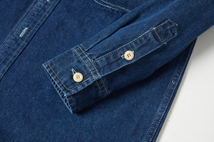 Dettaglio dei polsini di una camicia di jeans blu scuro con bottoni con incisione