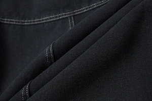 Detailopname van zwarte denimstof met contrasterende witte dubbele stiksels details