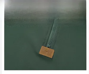 Primer plano de cuello con cremallera verde oscuro, tejido de nido de abeja y parche