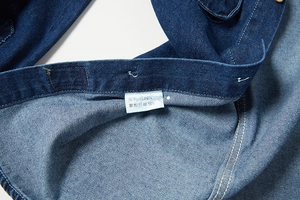 Dettaglio del tessuto denim blu con etichetta in cotone e cuciture di alta qualità