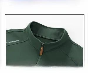 Detalle de jersey verde militar con cuello alto, cremallera metálica y tirador de cuero