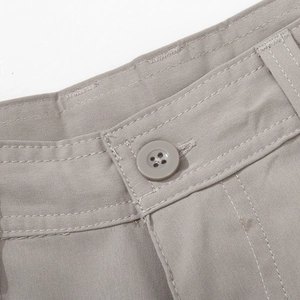 Detail of waist stitching and button closure on men's light grey cargo trousers