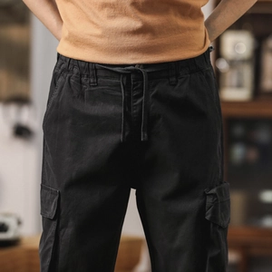 Detail view of cotton cargo pants showing elastic drawstring waist and side flap pockets
