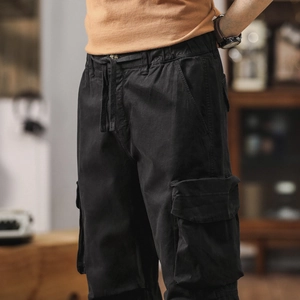 Detail of black cotton cargo pants featuring elastic drawstring waist and side flap pocket