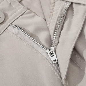 Detailed macro view of beige cargo pants featuring a sturdy silver zipper and resin button