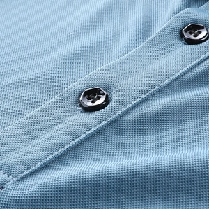 Close-up of light blue polo shirt collar showing black hexagonal buttons and mesh texture