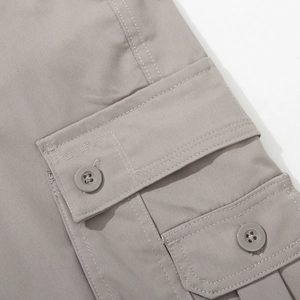 Detail of grey cargo pants showing double flap pockets with matching buttons and neat stitching
