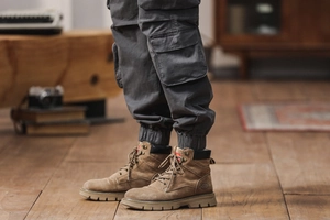 Detail of tan suede cargo boots with rugged rubber soles and branded logo accents