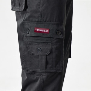 Detail of cargo pants side pocket with red fashion label on durable black fabric