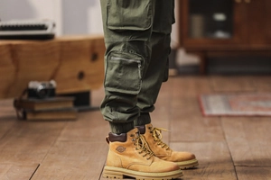 Detail view of dark green cargo pants with pockets paired with classic yellow boots