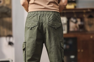 Detail view of military green cargo pants featuring an elastic waist and flap pockets