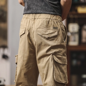 Detail view of khaki cotton cargo pants featuring elastic waist and large side pockets