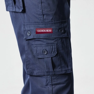 Detail of cargo pants side pocket with a red fashion label and navy twill fabric