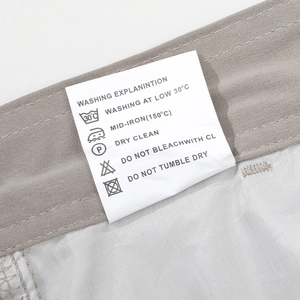 Close-up of washing instructions label with care symbols on khaki cargo trousers