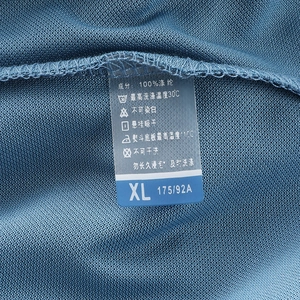 Detail of ice silk polo shirt showing mesh fabric texture and 100% polyester care label