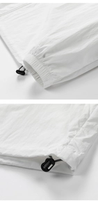 Detail of white sun protection jacket featuring adjustable black toggles and elastic cuffs