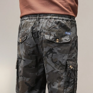 Dettaglio macro dei pantaloncini cargo mimetici da uomo con elastico in vita e tasche a bottone