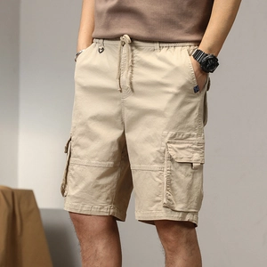 Dettaglio dei pantaloncini cargo kaki che mostra il tessuto in twill di cotone e le tasche