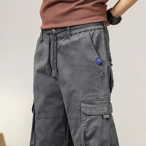 Detail view of elastic drawstring waist and large cargo pocket on dark grey trousers