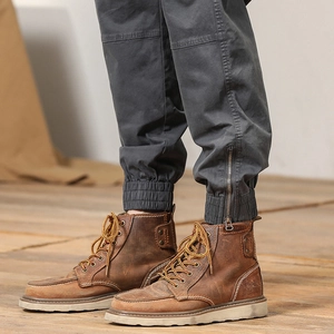 Detail of brown leather work boots and grey cargo joggers with ankle zipper accents